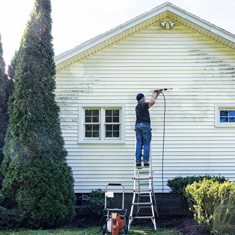 senior Man Up On Ladder DIY Power Washing House Siding